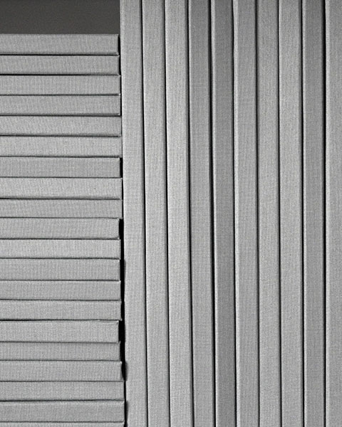 Graue textile Flächen mit regelmäßigen horizontalen und vertikalen Faltungen, nebeneinander angeordnet.