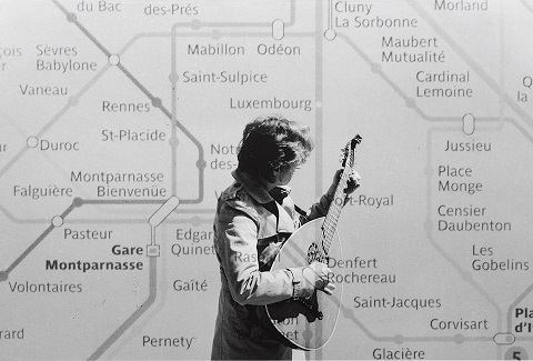 Kathleen Jahn spielt ein Saiteninstrument vor einem Wandplan der Pariser Métro.